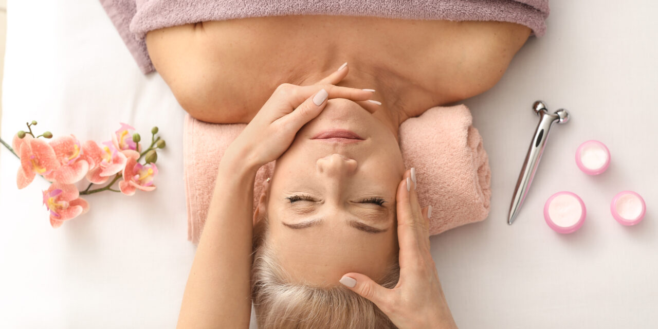 Mature woman receiving face massage in beauty salon