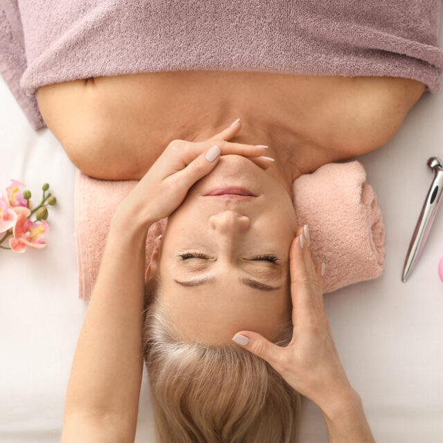 Mature woman receiving face massage in beauty salon