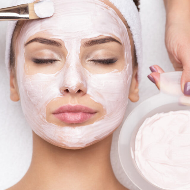 Young beautiful woman receiving  facial mask in spa beauty salon