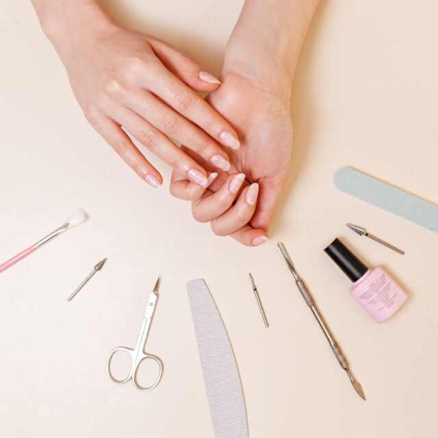 Medicine, cosmetology and manicure. A client in a nail salon demonstrates well-groomed nails after the procedure. White table with tools. Close up and flat line.