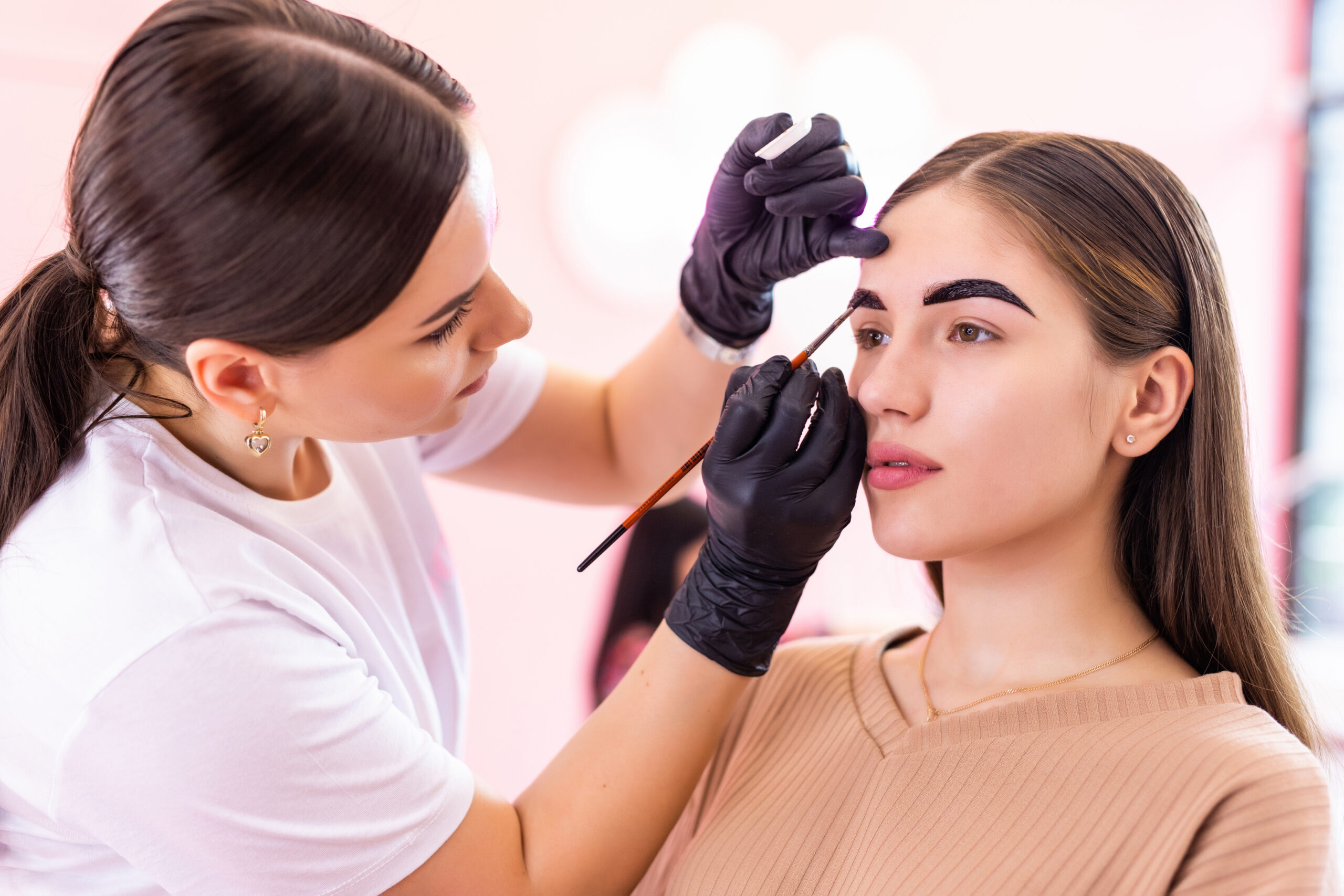 makeup artist applies paint henna on eyebrows in a beauty salon.