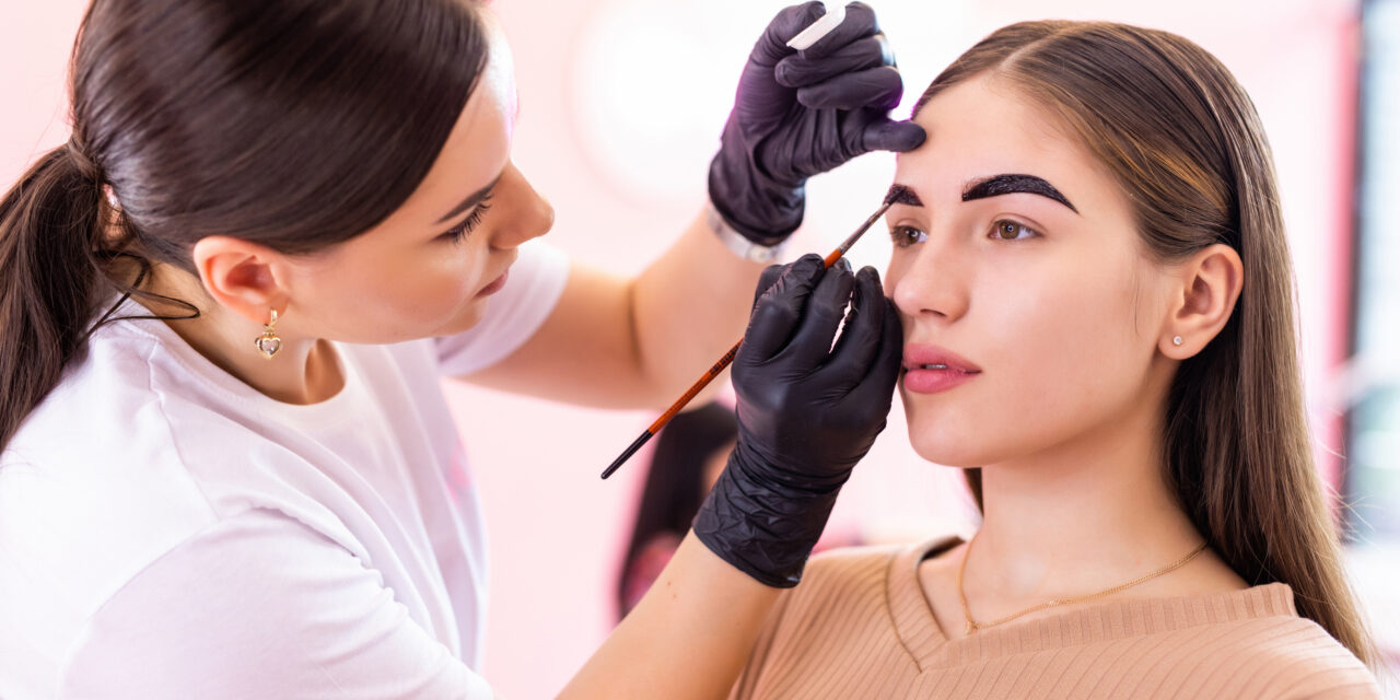 makeup artist applies paint henna on eyebrows in a beauty salon.